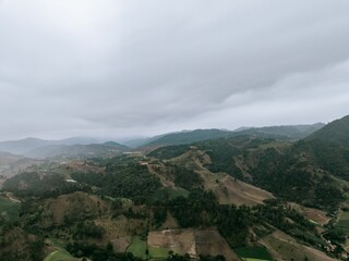 Aerial view of green hills under cloudy sky.