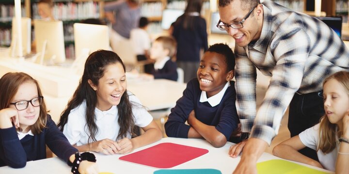 A diverse group of children and a teacher in a classroom, engaged and smiling. Classroom learning, diverse group, and teacher interaction. Education, learning, school concept with copy space.