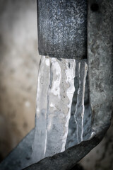Close-Up of Frozen Icicles Hanging from a Metal Drainpipe in Winter