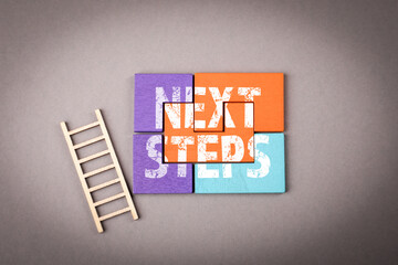 Next steps. Colorful wooden puzzle on a gray background