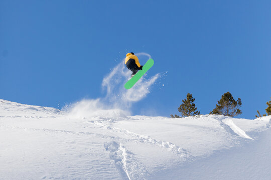 Snowboarder catching air on snowy slope under clear sky