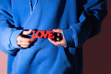 Hands holding love sign in blue hoodie close up