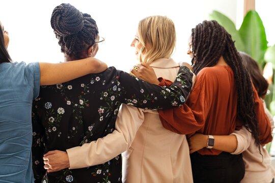 A diverse group of women, stand together, embracing friendship and unity. The women showcase solidarity and support, Diverse businesswomen team embracing friendship and unity together.