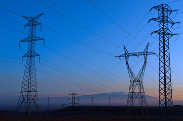 High voltage electricity pylons silhouetted against a twilight sky