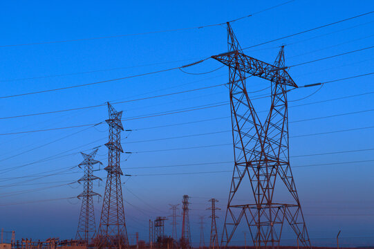 High voltage power lines at dusk against a clear sky
