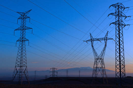 High voltage electricity pylons silhouetted against a twilight sky