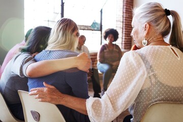 A diverse group in a support meeting, with people sitting in a circle. Participants include women...