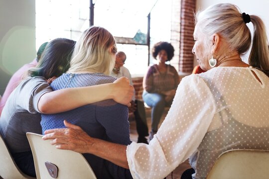 A diverse group in a support meeting, with people sitting in a circle. Participants include women and men, sharing and supporting each other in a bright room. Supportive diverse group.