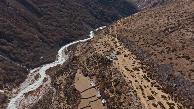Serpentine river cutting through lush valley, framing remote Nepalese settlement in Shomare to Dingboche Route under Himalayan peaks