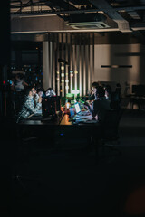 A group of business coworkers working together on a project in an office during nighttime, creating...