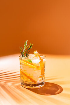 Refreshing cocktail with citrus and rosemary on orange background