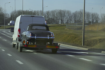 Transport of a black retro car on a trailer for the carriage of cars.
