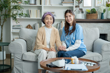 Friendly relationship between caregiver and happy elderly woman at home.caregiver holding hands helping for comfort,trust or patient for medical check or nursing.healthcare service,wellness concept