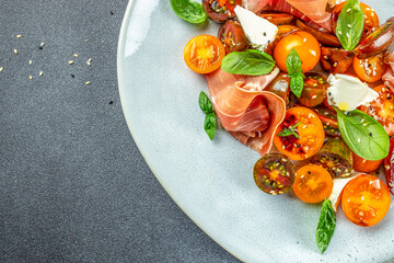 prosciutto salad, cherry tomatoes, and cream cheese with basil leaves, antipasto, Restaurant menu,...
