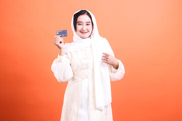 Confident Muslim Woman Displaying Debit Card for Online Shopping and Payments, showcasing Financial...