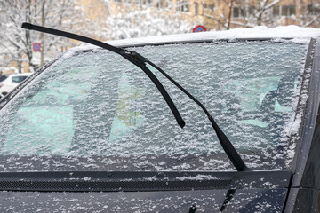 
car windshield and brooms covered with snow.