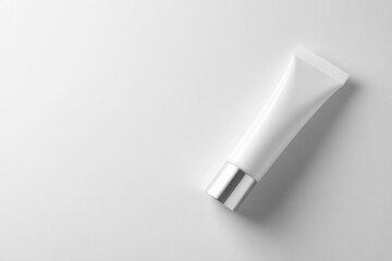 White background, top view of an eye cream tube on the right side of the composition, a white cosmetic bottle with a silver cap