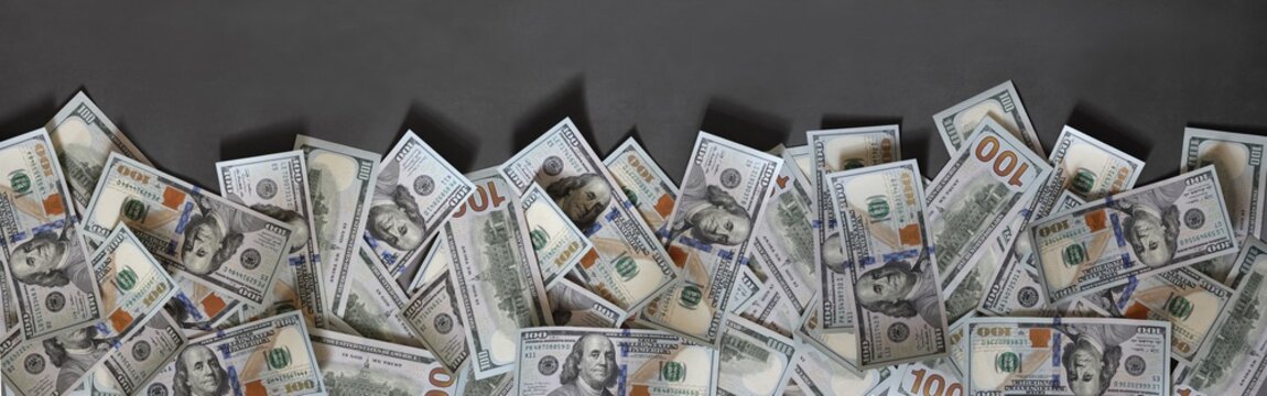 Cash American hundred dollar banknotes border on gray. Wide money background for fiancial concept.
