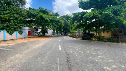 Ikeja, Nigeria - 16 November 2024: View of tranquil urban landscape with empty road, trees, and buildings under a cloudy sky, Ikeja, Nigeria.