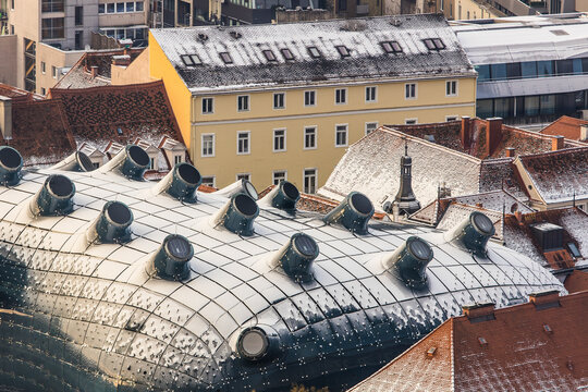 View of snowy rooftops and contemporary design of the kunsthaus, Graz, Austria.