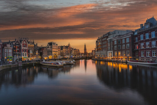 Amsterdam, The Netherlands - 13 April 2022: View of charming houses at water canal with vibrant reflections and historic buildings, Amsterdam, The Netherlands.
