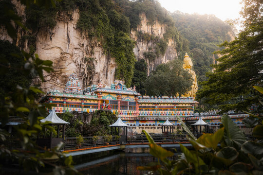 View of Batu Caves with majestic golden statue and lush greenery, Kuala Lumpur, Malaysia.