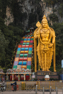 Kuala Lumpur, Malaysia - 13 August 2022: View of colorful stairs leading to the golden statue of Murugan at Batu Caves, Kuala Lumpur, Malaysia.
