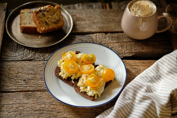 rye bread toast with scrambled eggs and yellow cherry tomatoes