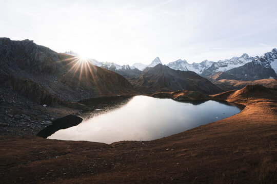 View of serene Lacs de Fenetre with majestic mountains at sunset, La Fouly, Switzerland.