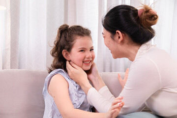 Mother and daughter share an intimate and heartwarming moment, smiling and enjoying their close bond in a cozy home setting, adorable girl enjoys gentle manicure from her caring mother with love.