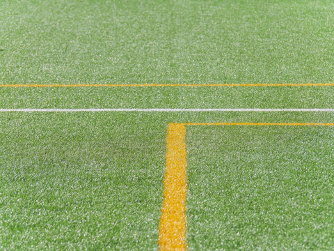 Vibrant green artificial turf soccer field with yellow and white lines