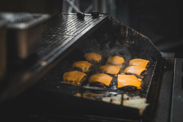 Juicy burgers and sizzling meat on a smoky grill at a vibrant outdoor food festival