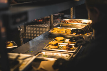Juicy burgers and sizzling meat on a smoky grill at a vibrant outdoor food festival