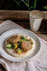 Flatbread with chickpea patty, cherry tomatoes, lettuce, cucumber, cilantro and sesame seeds