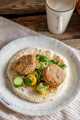 Flatbread with chickpea patty, cherry tomatoes, lettuce, cucumber, cilantro and sesame seeds