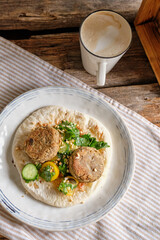 Flatbread with chickpea patty, cherry tomatoes, lettuce, cucumber, cilantro and sesame seeds