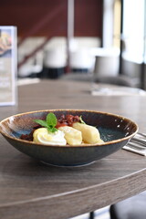 A traditional Czech sweet dish featuring potato dumplings, known as bramborové šišky, served with creamy quark cheese and ripe plums.