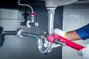 Plumber hands holding wrench doing repairing work at the sink and clogged pipe in bathroom carefully