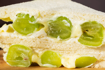 Korean sandwich with green grape and cream cheese, closeup. Hard light. Asian dessert, street food.