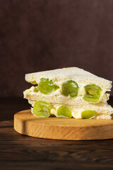 Korean dessert sandwich with green grape and cream cheese on a wooden board. Hard light. Asian breakfast, street food. Vertical orientation.