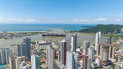 Cargo ship maneuvering in front of the large and modern city of Itajaí, with its grand skyscrapers.