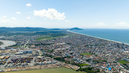 Panoramic photograph of Navegantes Airport, the city of Penha, and the Atlantic Ocean in the background.