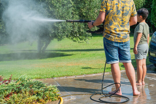 Father and child cleaning garden with pressure washer for the summer - Powered by Adobe