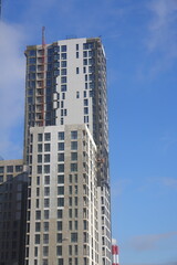 Fototapeta premium construction cradle on the facade of a building under construction, new building in a residential area, sunny day, Moscow, February 2025, 2