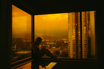 Woman on a mobile phone in hotel room against urban sunset backdrop