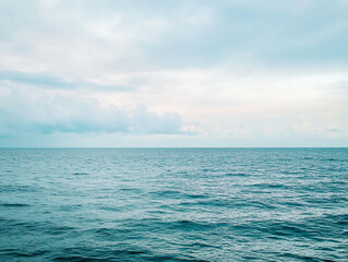 Obraz premium A peaceful view of the endless ocean meeting the sky, with gentle waves and soft clouds creating a calming and tranquil seascape