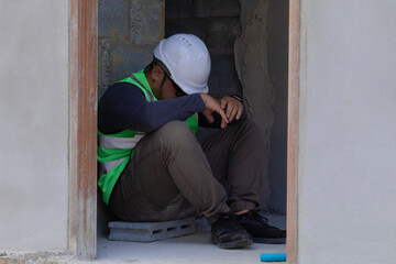 Asian engineering contractors working wearing safety vests and helmets inspect construction site tired and discouraged take a break, drinks water while working at construction site.
