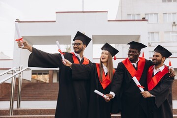 Diverse Group of Happy Graduates Celebrating Achievement with Diplomas in Academic Caps and Gowns...