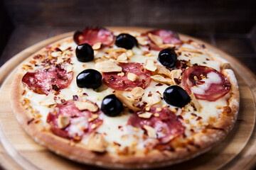 Pizza with salami and mozzarella cheese. Wooden background. Soft focus. Close up.	