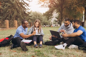 Diverse Group of College Students Studying and Collaborating Outdoors on Campus Lawn